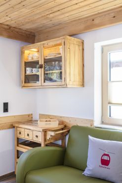 Blick in die Wohnküche der Ferienwohnung Wildseeloder mit grüner Ledercouch und Holzschrank..