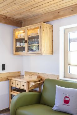 Blick in die Wohnküche der Ferienwohnung Wildseeloder mit grüner Ledercouch und Holzschrank..